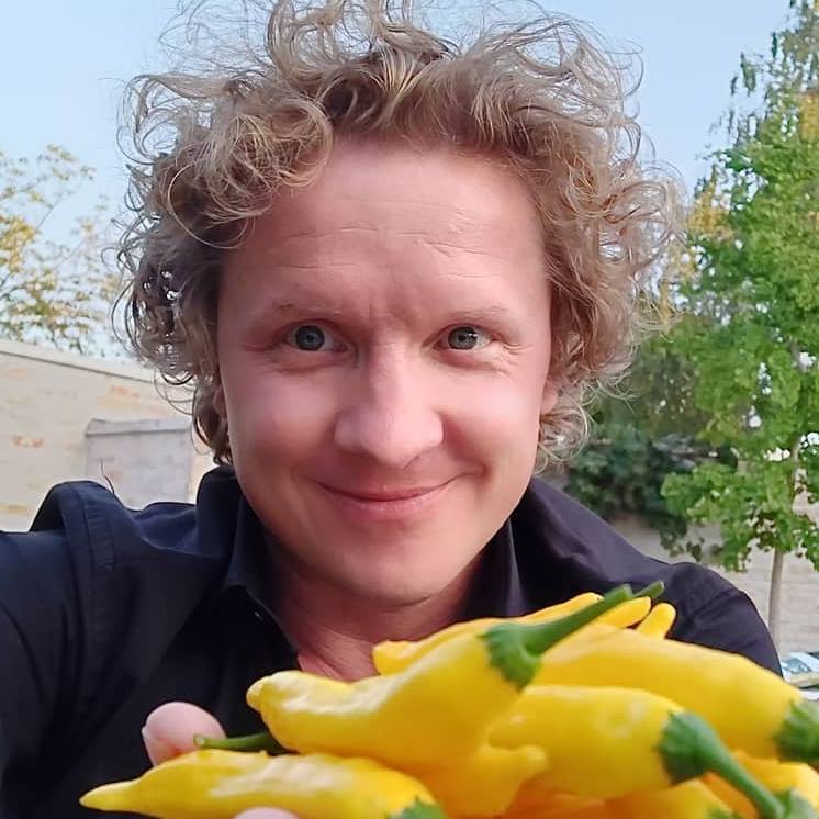 Magnus holding up a fist of home grown Lemon Drop Chilies.